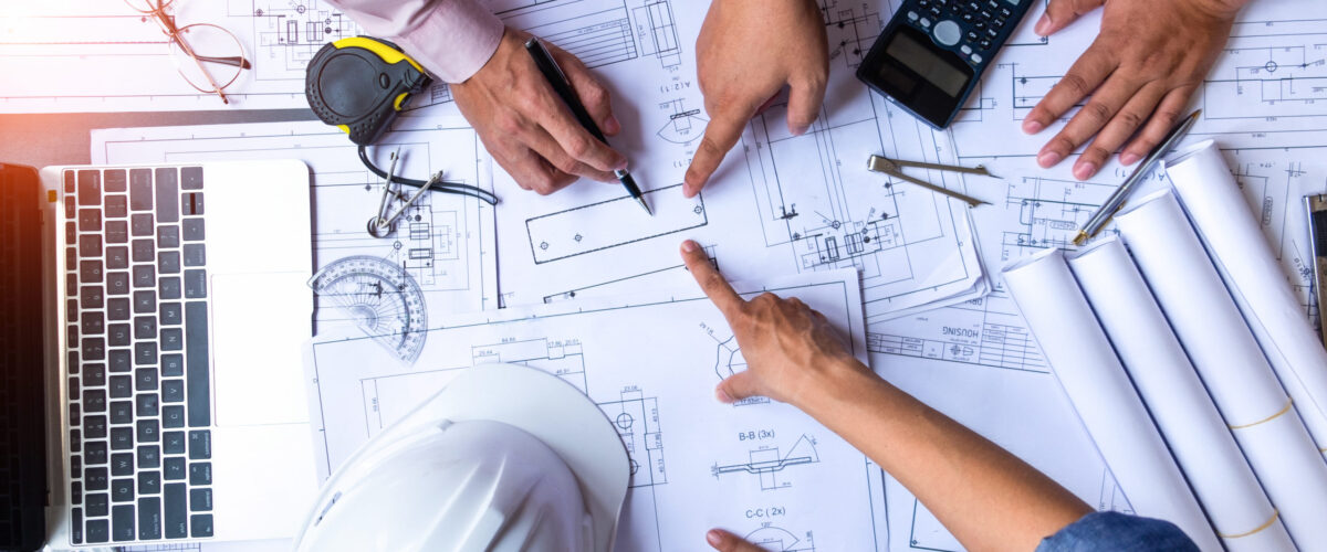 engineers pointing to building on blueprint and using laptop to drawing design building Project in office, construction concept. Engineer concept